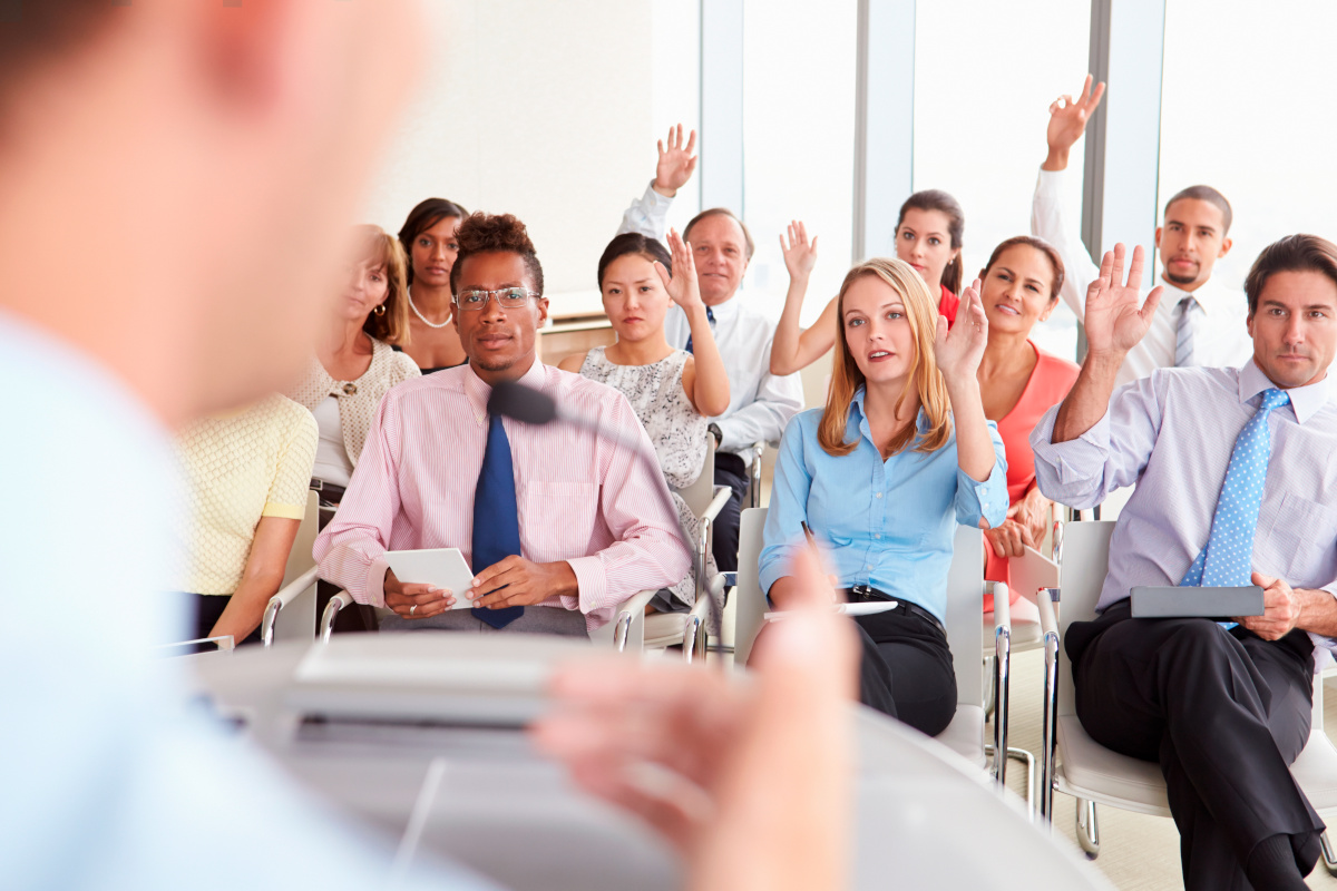 Business people raising their arms to ask questions at a business conference