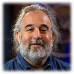 Adam Gordon, Microsoft Certified Learning Consultant, headshot with gray beard and blue shirt against blurred conference room background