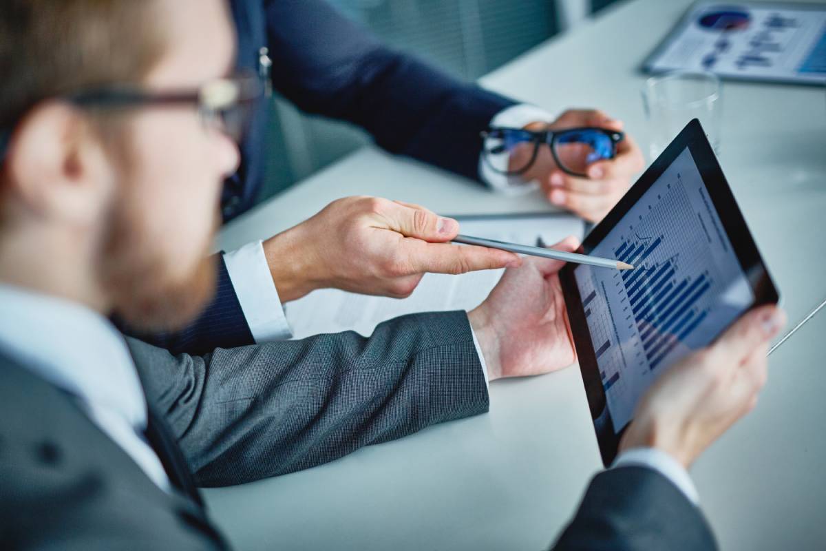 Businessmen looking at graph on a tablet showing increased sales