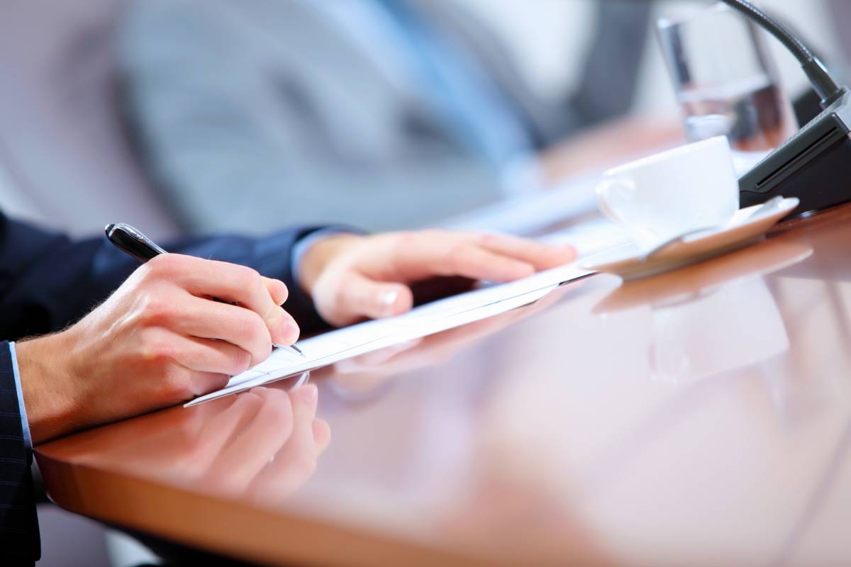 Close up view of a businessman writing on a piece of paper at his desk