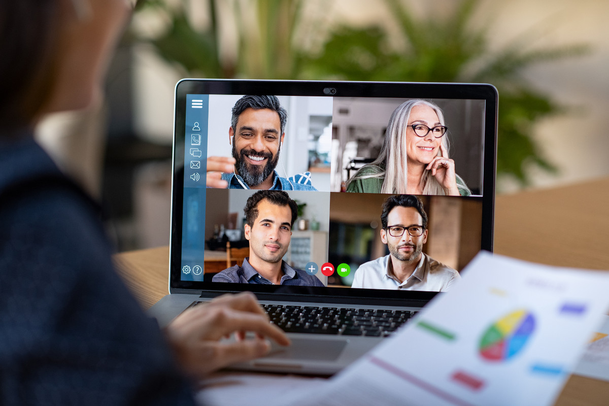 Woman using her laptop to have a video conference call with four co-workers, while working remotely